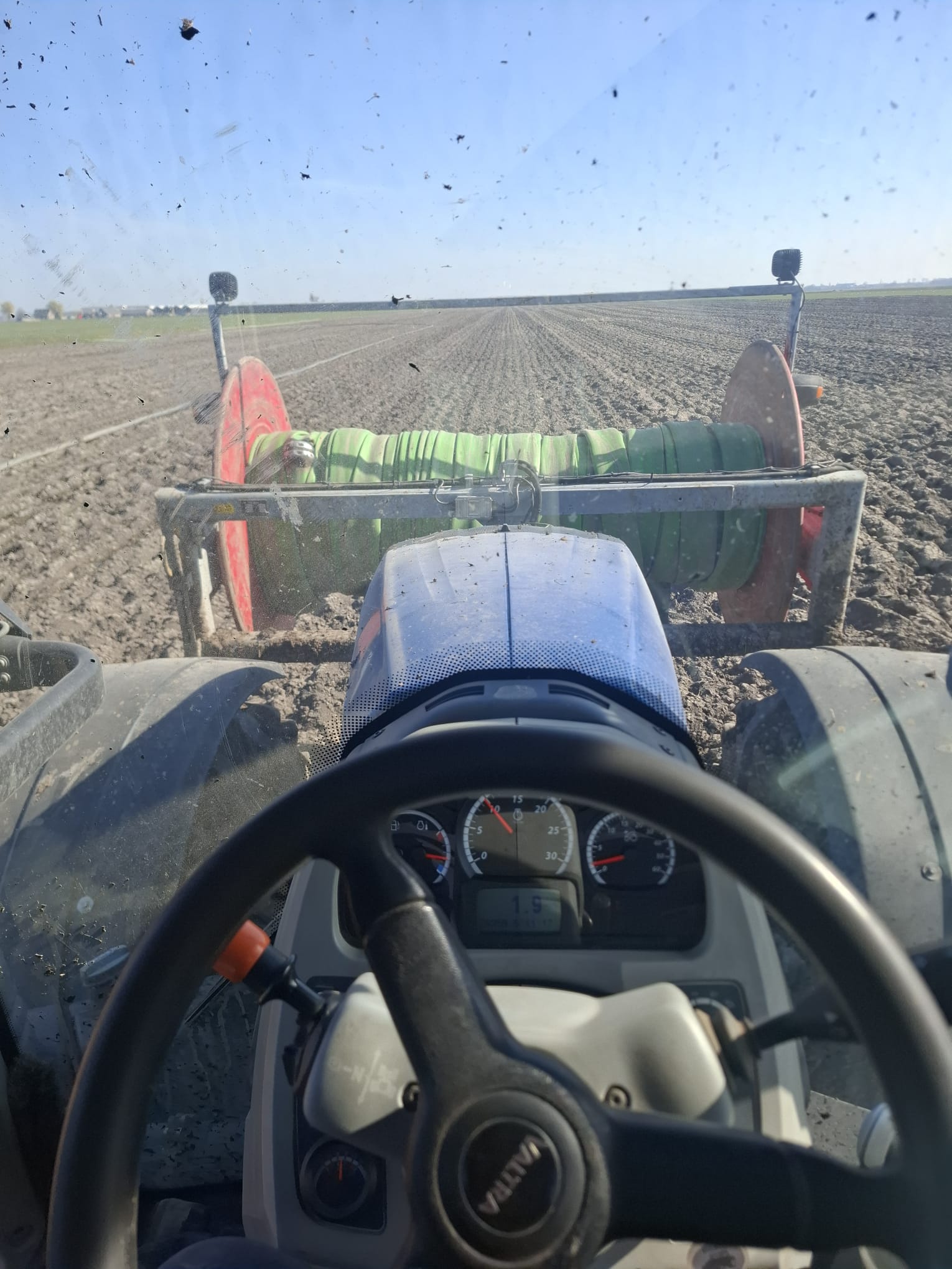 Uitzicht vanuit de Valtra-cabine over de slanghaspel en een omgeploegde akker